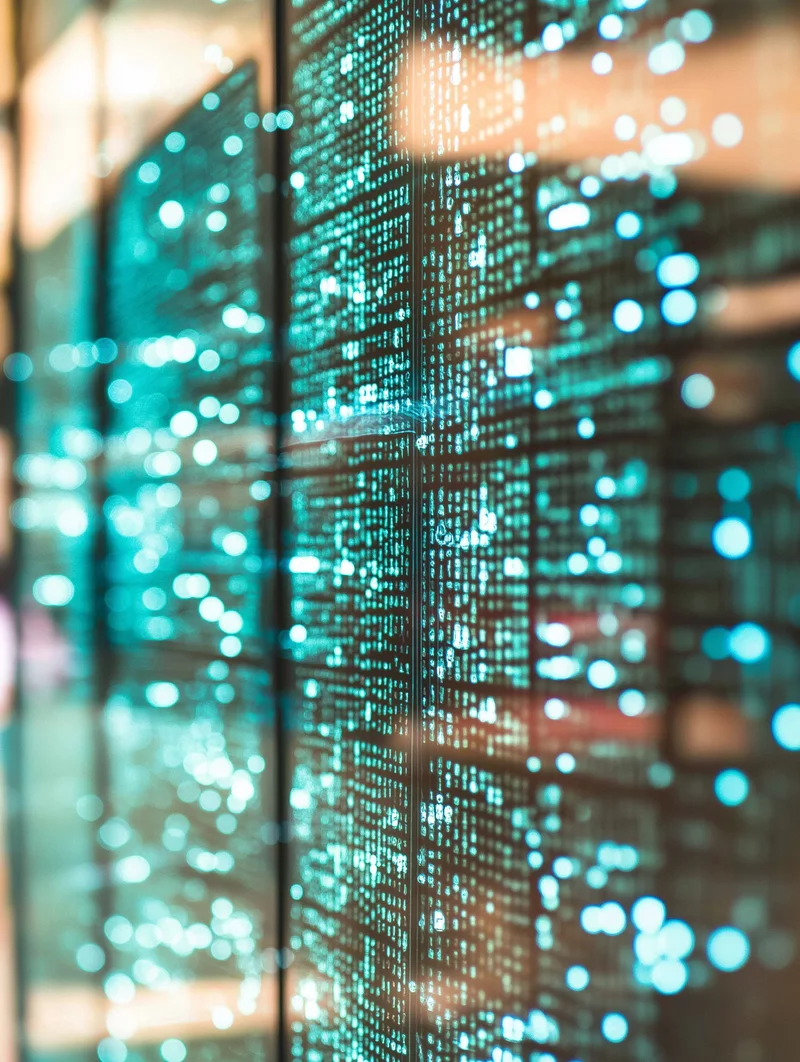 Zbliżenie na nowoczesne ekrany z jasnoniebieskimi punktami i ciągami cyfr, tworzącymi cyfrowy, futurystyczny klimat danych i analizy.